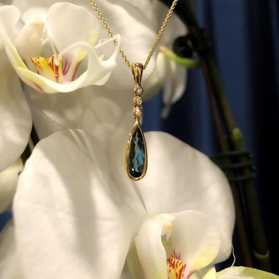Photo of Stanton Color Teardrop London Blue Topaz and Diamond Pendant in a decorative scene, designed by , available at Plumb Gold & Plumb Silver