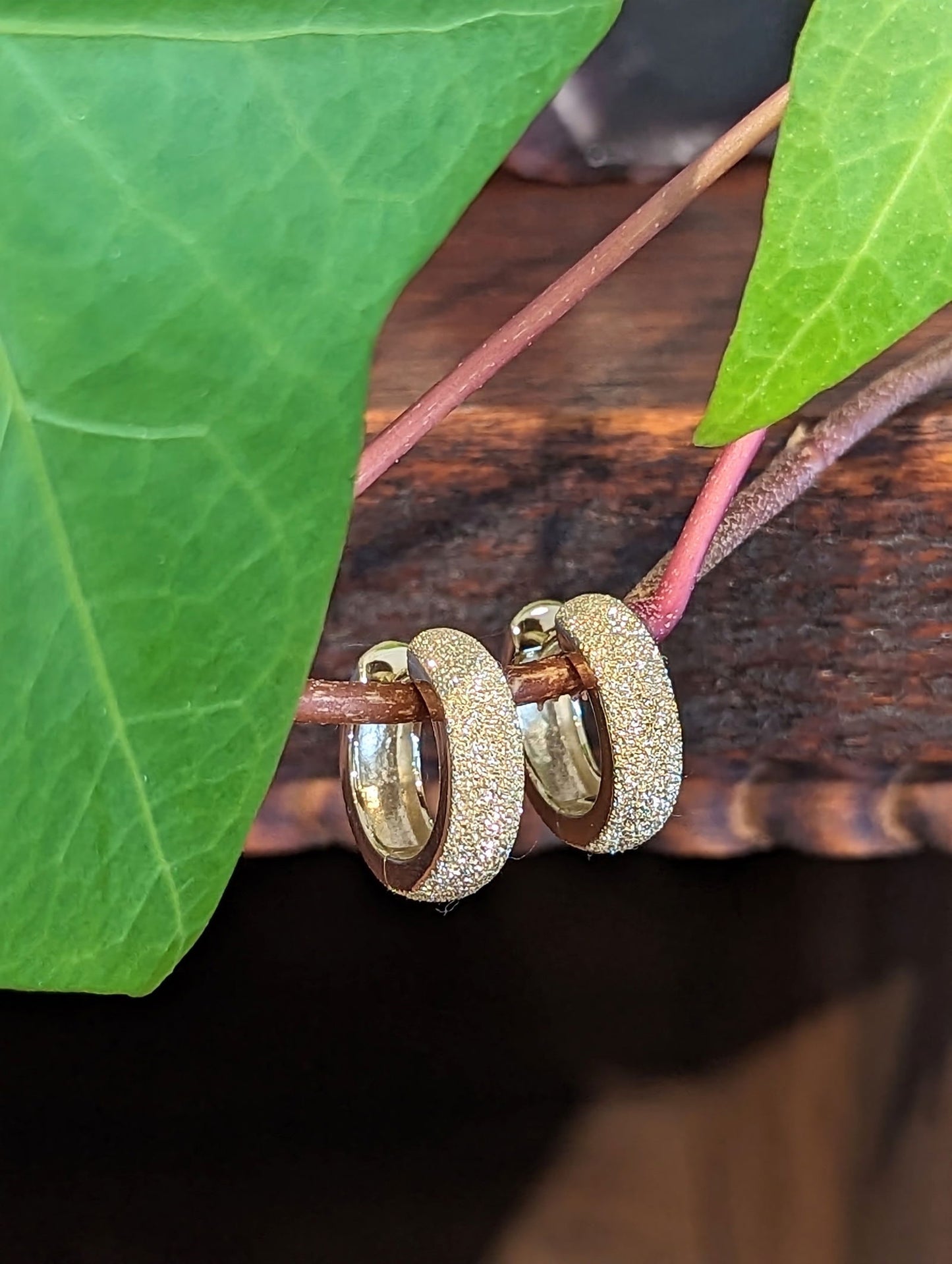 Photo of Stardust Huggie Hoops in a decorative scene, designed by , available at Plumb Gold & Plumb Silver