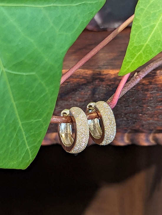 Photo of Stardust Huggie Hoops in a decorative scene, designed by , available at Plumb Gold & Plumb Silver