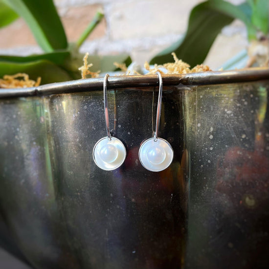 Photo of "Sun Glow" Pearl Earrings in a decorative scene, designed by , available at Plumb Gold & Plumb Silver