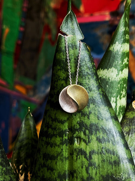 Photo of "Sun" Necklace in a decorative scene, designed by , available at Plumb Gold & Plumb Silver