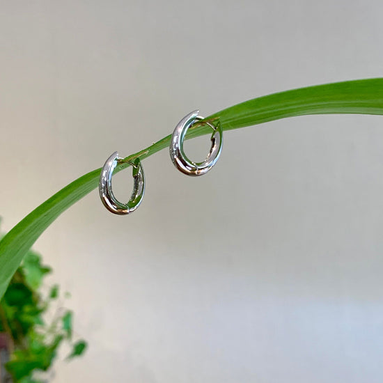 Photo of Tapered Huggie Hoops in a decorative scene, designed by , available at Plumb Gold & Plumb Silver