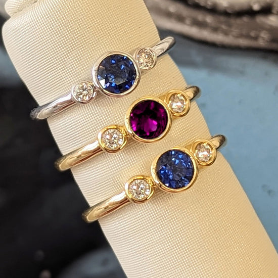 Photo of Three Stone Bezel Ring in a decorative scene, designed by , available at Plumb Gold & Plumb Silver
