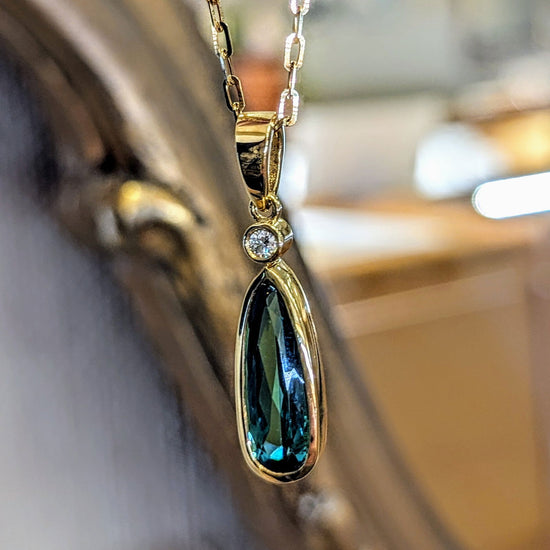 Photo of Tourmaline Drop Pendant in a decorative scene, designed by , available at Plumb Gold & Plumb Silver