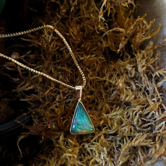 Photo of Trilliant Ethopian Opal Pendant in a decorative scene, designed by , available at Plumb Gold & Plumb Silver