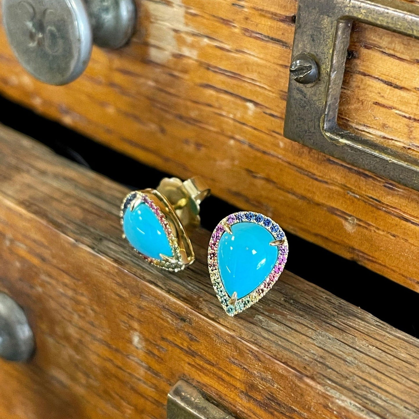 Photo of Turquoise and Rainbow Sapphire Studs in a decorative scene, designed by , available at Plumb Gold & Plumb Silver