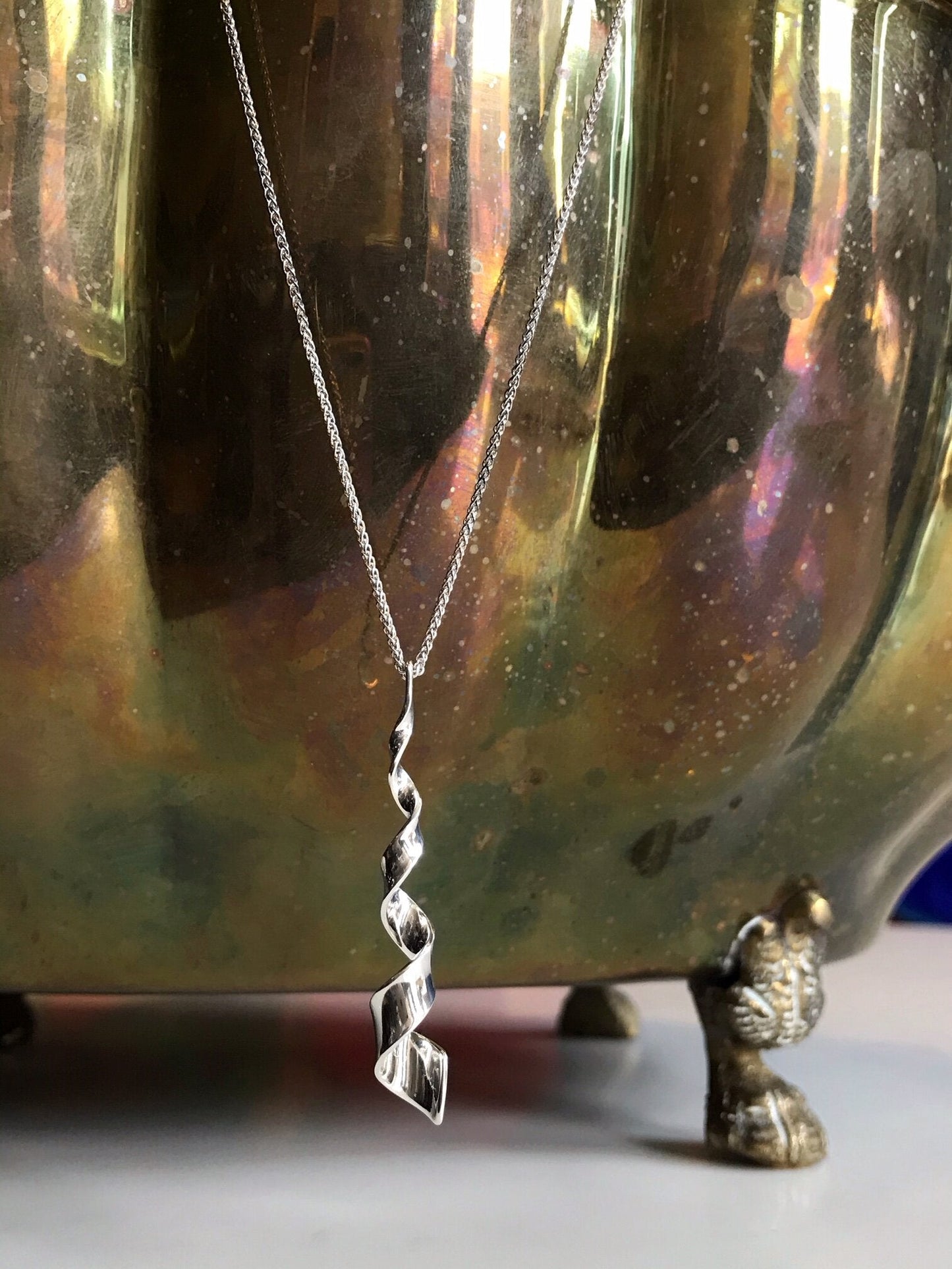 Photo of "Twist" Necklace in a decorative scene, designed by , available at Plumb Gold & Plumb Silver