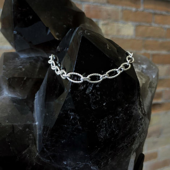 Photo of Twisted Oval Link Bracelet in a decorative scene, designed by , available at Plumb Gold & Plumb Silver