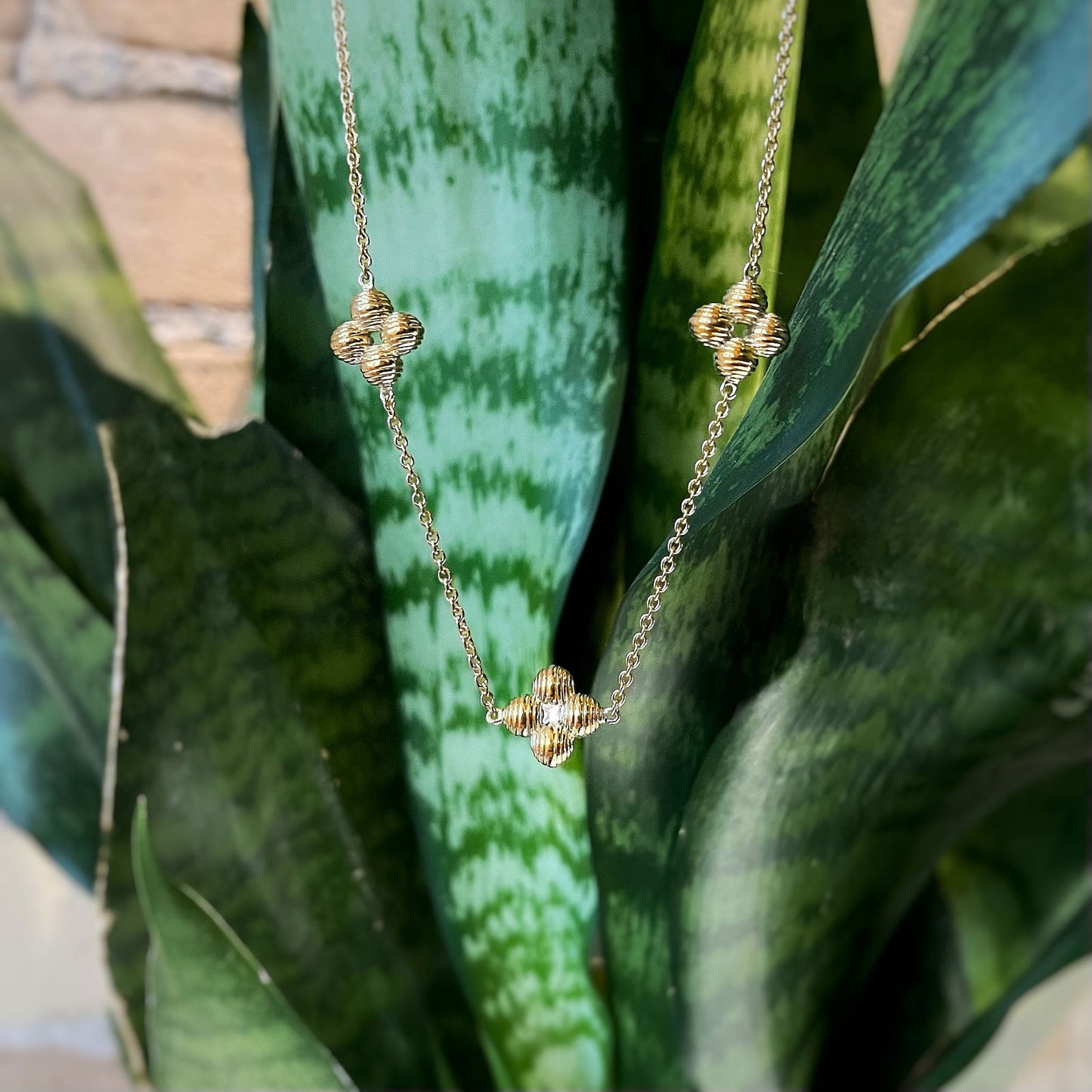 Photo of White Sapphire Clover Necklace in a decorative scene, designed by , available at Plumb Gold & Plumb Silver