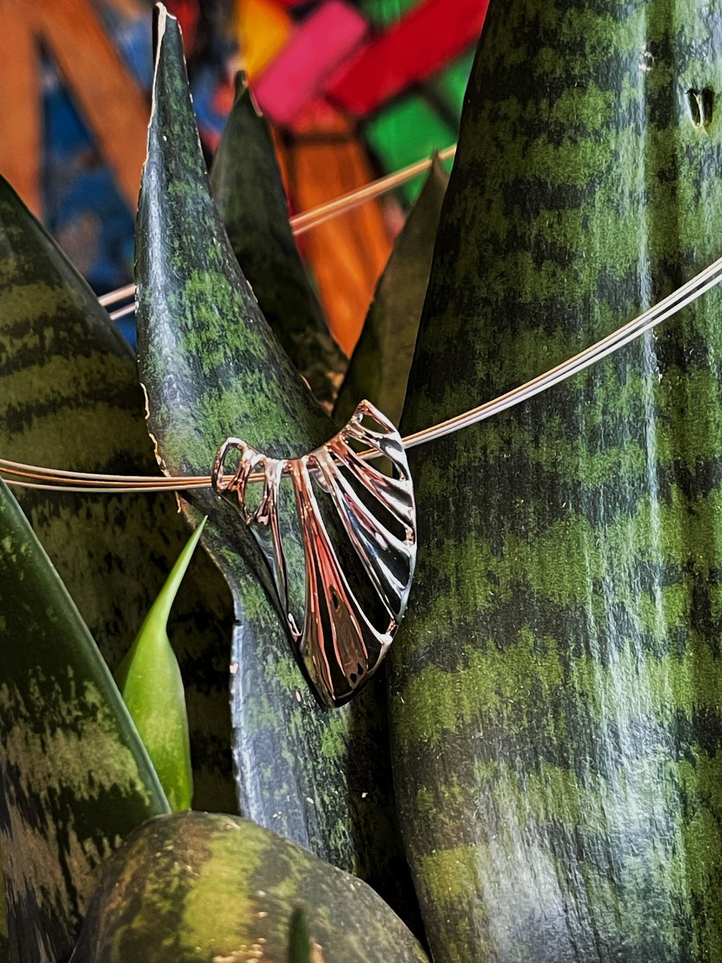 Photo of "Wing" Pendant in a decorative scene, designed by , available at Plumb Gold & Plumb Silver