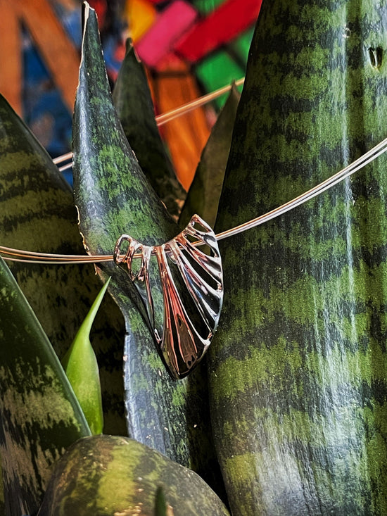 Photo of "Wing" Pendant in a decorative scene, designed by , available at Plumb Gold & Plumb Silver