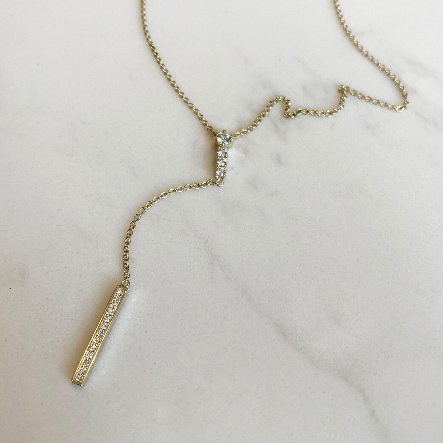 Photo of "Y" Diamond Stick Necklace in a decorative scene, designed by , available at Plumb Gold & Plumb Silver