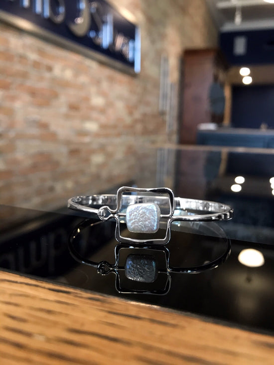 Photo of "Zenith" Bangle in a decorative scene, designed by , available at Plumb Gold & Plumb Silver