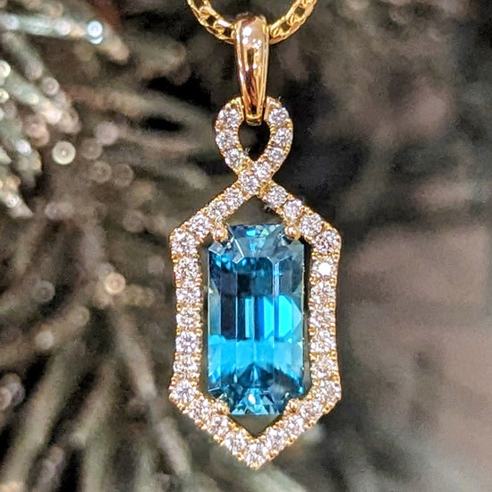 Photo of Zoma Blue Zircon Halo Pendant in a decorative scene, designed by , available at Plumb Gold & Plumb Silver