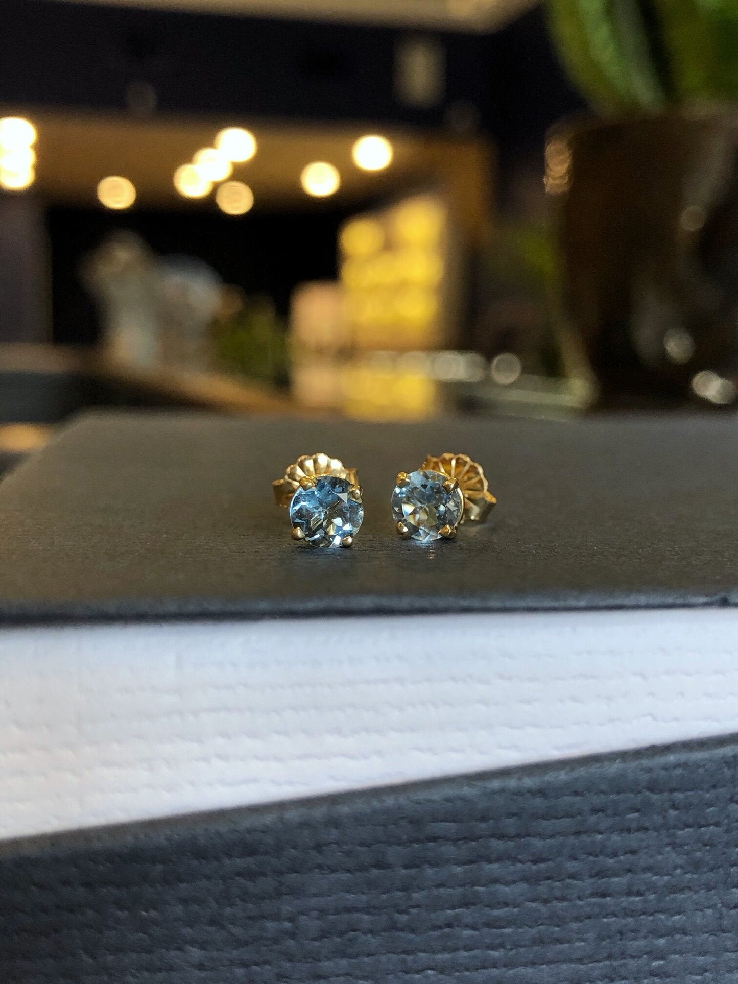 Photo of Zoma Color Aquamarine Studs in a decorative scene, designed by , available at Plumb Gold & Plumb Silver