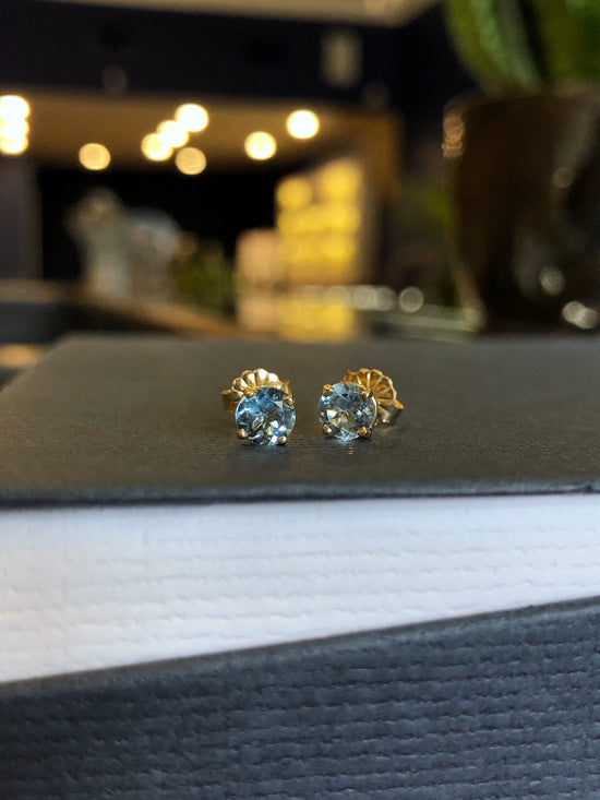 Photo of Zoma Color Aquamarine Studs in a decorative scene, designed by , available at Plumb Gold & Plumb Silver