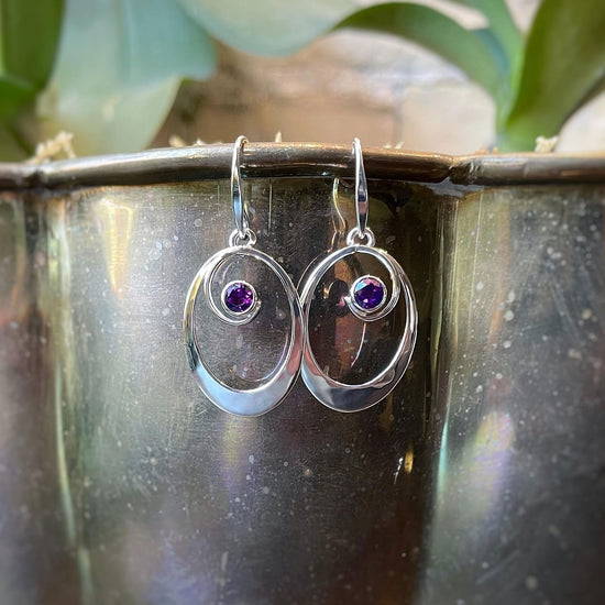 Photo of ophia Oval Amethyst Drop Earrings in a decorative scene, designed by , available at Plumb Gold & Plumb Silver