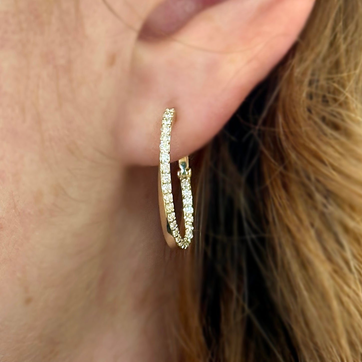 gold diamond earring on persons ear